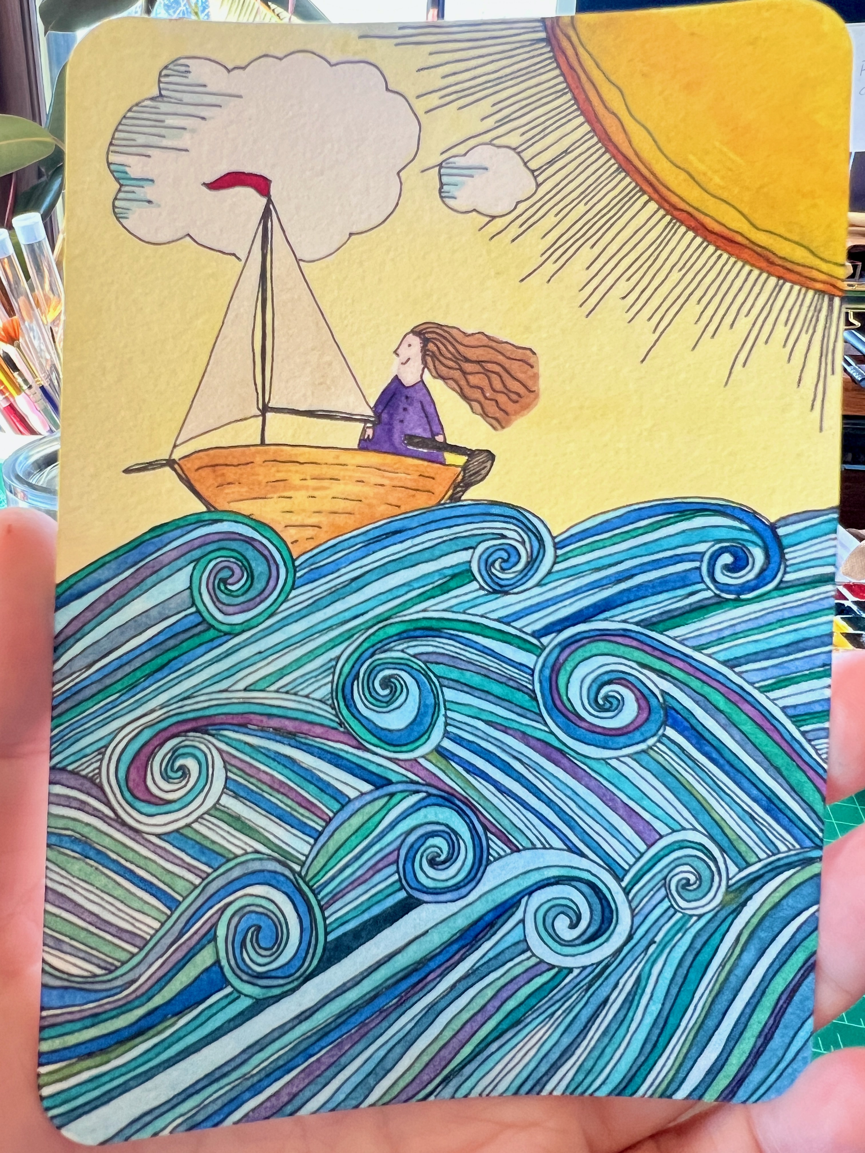 postcard with hand drawn pen and ink image of a woman in a tiny sailboat on seas with many layers of curling waves - she is happy and the sun is shining.